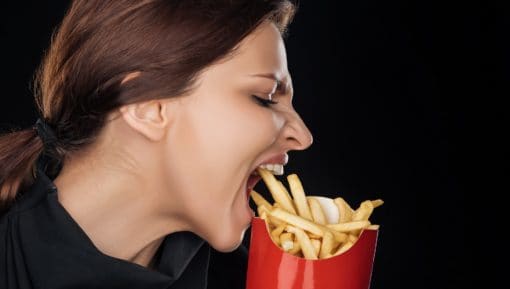 Emotional woman eating tasty french fries