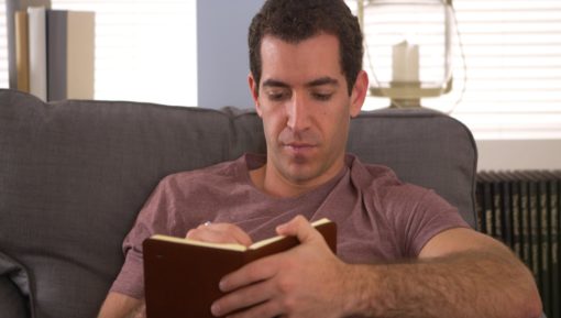 Man writing down thoughts in journal