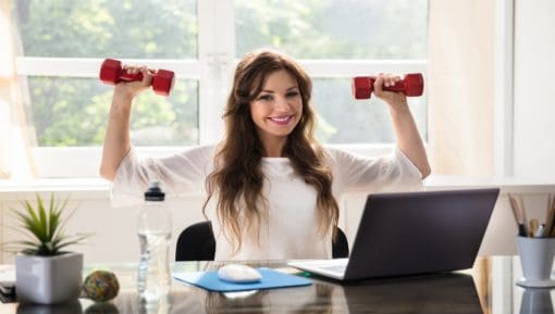 Smiling Young Businesswoman Exercising With Red Dumbbells