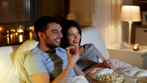 Couple with popcorn watching tv at night