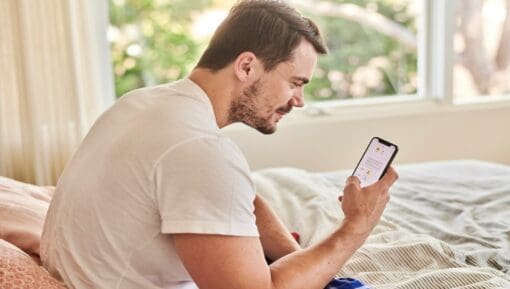 Photo of a man in bed checking his phone